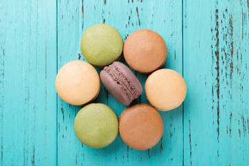 top view studio shoot of colorful macaroons shaped like a flower on blue wood background