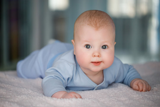 Portrait of a baby boy who lies on his stomach in a blue suit