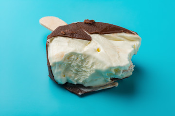 side view chocolate outer ice cream with some bites on a blue background close up