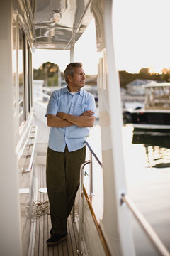 Mature man looking serious as he stands on a boat deck with his arms folded