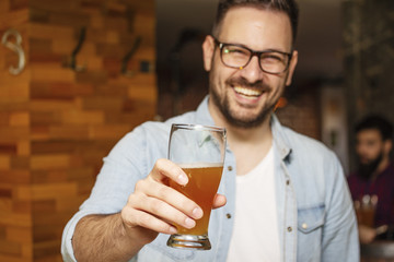 Young man holding glass of beer and smile