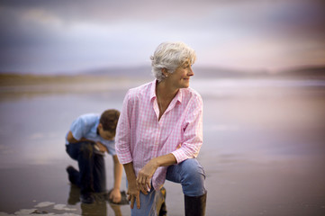 Elderly woman watching the sunset at the beach with her grandson.