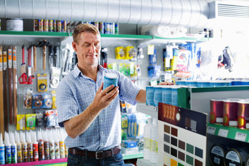 Portrait of male customer selecting paint can in housewares department