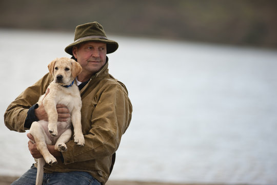 Portrait of man on beach holding a puppy.