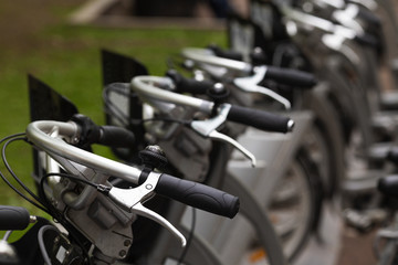 Close up of bike handlebars. Public bicycles are standing in bicycle sharing system in a row