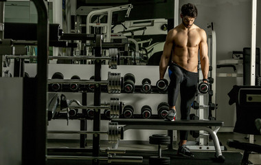 Fototapeta na wymiar Strong and handsome young man doing exercise with dumbbells