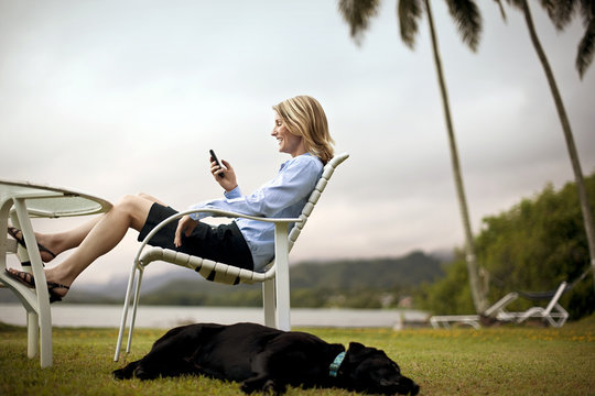 Mid-adult businesswoman text messaging while sitting by the sea.