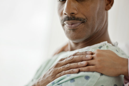 Hospital Patient Touches The Comforting Hand Laid On His Shoulder.