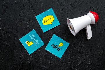 Socail media announcements concept. Megaphone near social media icons on black background top view