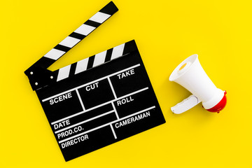 Naklejka premium Film director, producer concept. Filming. Electronic megaphone and clapperbord on yellow background top view