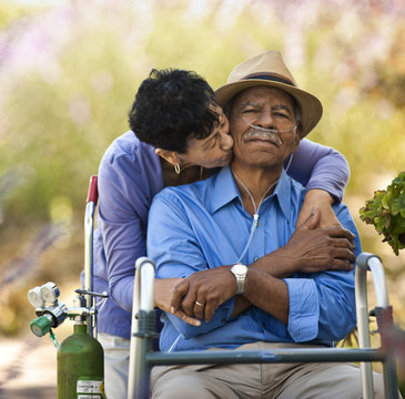 Senior woman kissing her husband with nasal tubes.