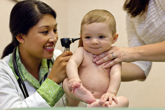 Doctor examining baby boy's ear with otoscope