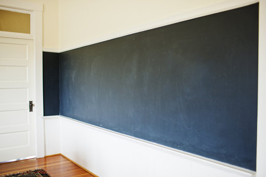 Empty chalkboard covering the wall of a classroom.