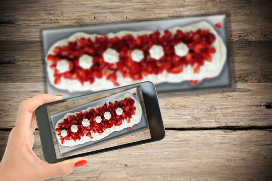 Take smartphone picture of a perfect Pavlova cake with meringue, cream and strawberries
