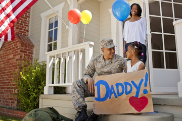 Happy young girl and her father sitting together on the front porch of their home.