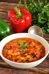 Delicious Letcho with fresh vegetables in a white bowl on a wooden background