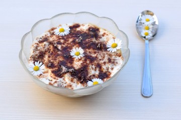 Tiramisu dessert in glass bowl, decorated with daisies flowers