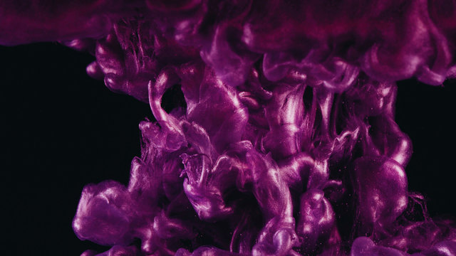 Ink in water. Colour pink glitter paint reacting in water creating abstract cloud formations.