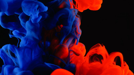 Red and blue ink in water shooting with high speed camera. Bloody paint dropped, reacting, creating abstract cloud formations and metamorphosis on black. Art backgrounds.