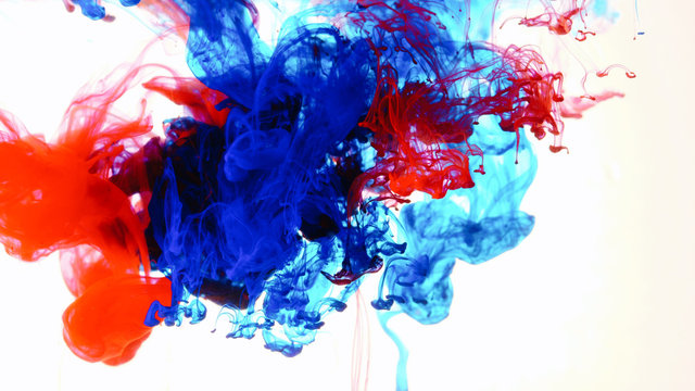 Red and blue ink in water shooting with high speed camera. Indigo paint dropped, reacting, creating abstract cloud formations metamorphosis on white. Art backgrounds