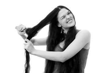 A young woman can not comb out the problematic tangled hair. White background close up