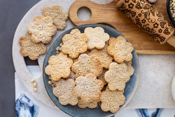 On the plate is a curly cookie with decorative patterns made with a wooden rolling pin