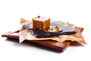 Dessert with caramel and hazelnut on a black pedestal isolated on white background.