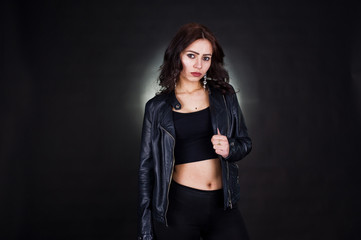 Obraz na płótnie Canvas Studio portrait of sexy brunette girl in black leather jacket against black background.