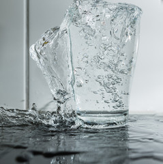 Wasser spritzt aus dem Glas - überfülltes Glas mit Trinkwasser als Erfrischung 