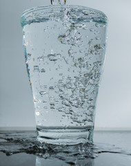 überfülltes Glas mit Wasser - Trinkwasser überlauft aus Glas