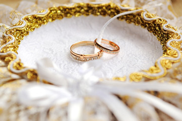 Gold wedding rings on a cushion. Wedding day.