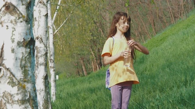 The girl is walking in the park. A child with a yellow flower in nature.