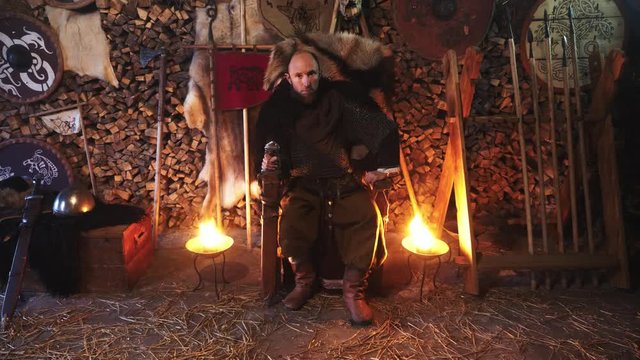 Portrait of a Viking warrior seated on a throne with a sword in his hands.