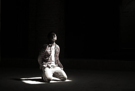 Man kneeling in a bright beam of light in a mosque in Iran