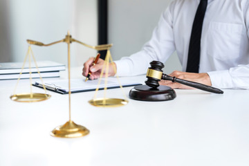 Businessman or lawyer working on a documents, judge gavel with Justice lawyers at law firm in background, Legal law, advice and justice concept