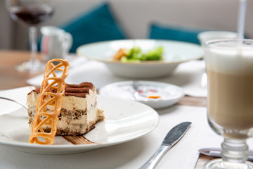 Beautiful piece of delicious tiramisu with caramel chips and latte in a cafe.