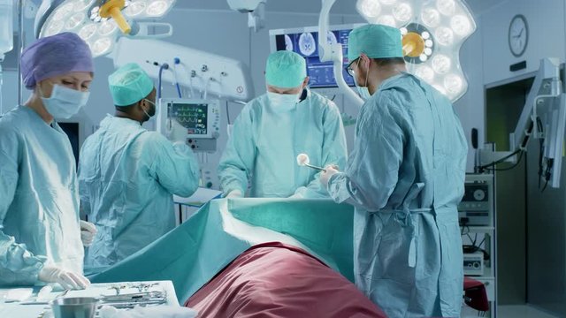 High Angle Shot of Diverse Team of Professional surgeon,  Assistants and Nurses Performing Invasive Surgery on a Patient in the Hospital Operating Room. Shot on RED EPIC-W 8K.