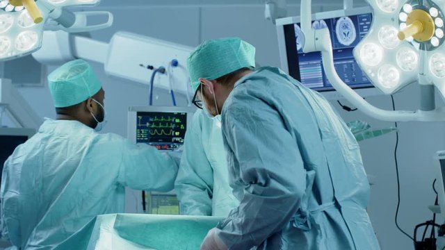 Diverse Team of Professional surgeon,  Assistants and Nurses Performing Invasive Surgery on a Patient in the Hospital Operating Room. Shot on RED EPIC-W 8K.