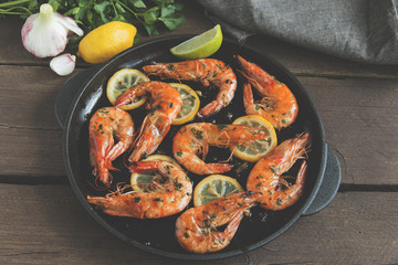 fried roasted shrimps in frying pan with lemon greens parsley garlic