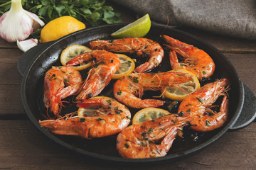 fried roasted shrimps in frying pan with lemon greens parsley garlic