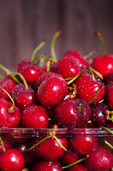 Sweet red cherries in glass bowl on dark wooden backgound with copy space. Summer and harvest concept. Vegan, vegetarian, raw food