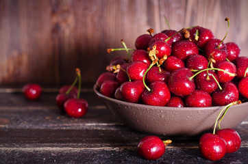 Fresh cherries in plate on dark wooden background with copy space. Summer and harvest concept. Cherry macro. Vegan, vegetarian, raw food