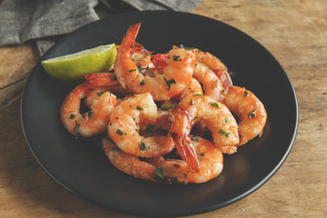 fried roasted shrimps in plate with lemon greens parsley garlic