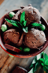 Three scoops of dark chocolate ice cream sundae with mint leaves and peanuts