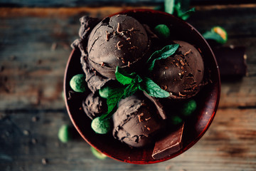 Three scoops of dark chocolate ice cream sundae with mint leaves and peanuts