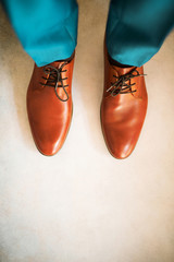 Man wearing shoes on gray background. Clothing concept, groom getting ready before ceremony. Body detail of businessman.