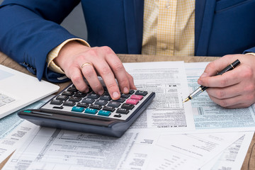 Businessman works with W-4 tax form and calculator