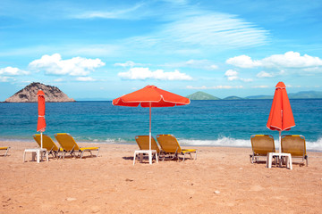 Abstract image with sun loungers and orange umbrellas from the sun on the beach on the seafront with waves (relaxation, harmony, holidays - concept)