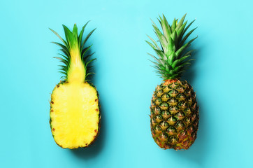 Whole pineapple and half sliced fruit on blue background. Top View. Copy Space. Bright pineapples...