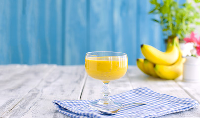 Smoothies of banana, blue napkin and wooden background.Banner. Place for text